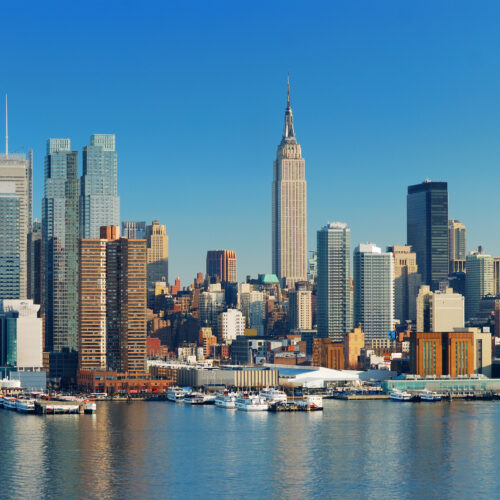 Manhattan Skyline with Empire State Building, New York City over Hudson River with boat and pier.